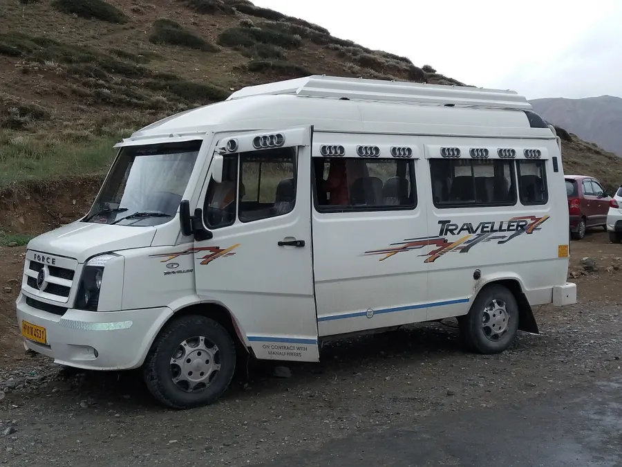 A white tempo traveller van parked beside a mountain road